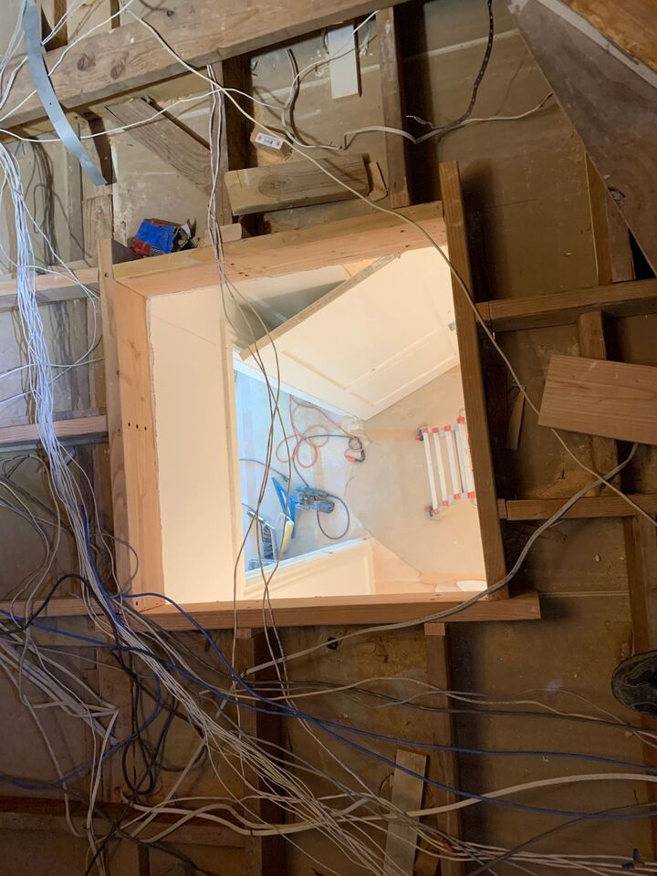 Attic space above the new hatch with insulation board and wiring visible around the framed opening