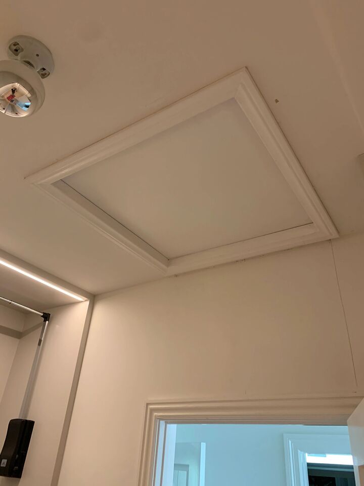 Finished attic hatch trimmed flush into the ceiling with a smooth painted surround