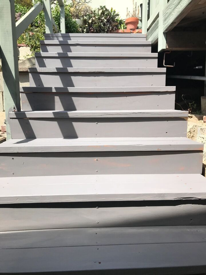 Grey painted exterior stair treads running down beside a house in strong sunlight