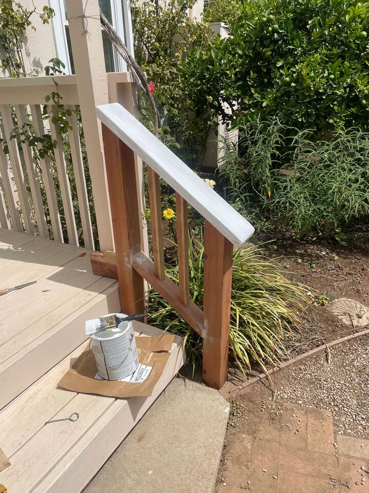 Timber porch corner with new handrail post and decking boards, tools still on the deck