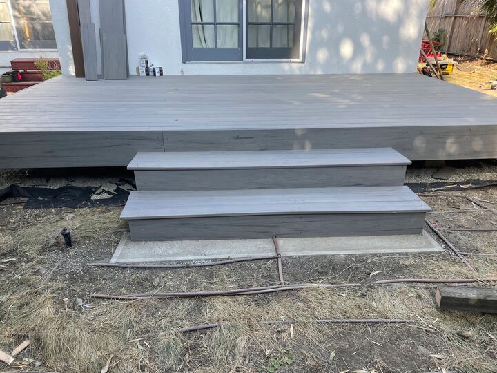 Low grey deck platform with two wide steps down to the yard, still under construction