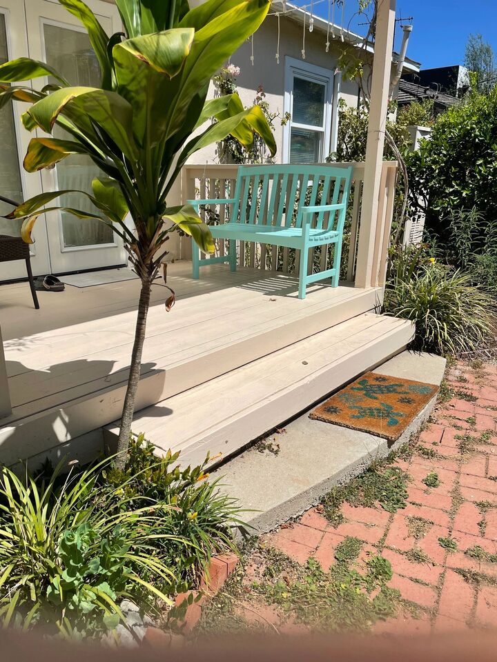 Front porch with a painted bench, potted palm and new step edge onto a brick path