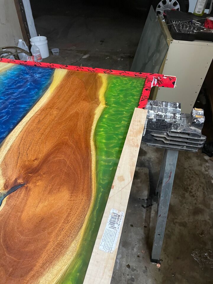 Resin table top on a workbench with a straightedge laid across it during levelling