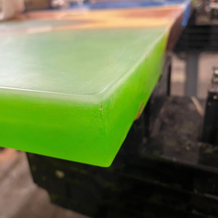 Close corner detail of the translucent green resin edge against the polished wood
