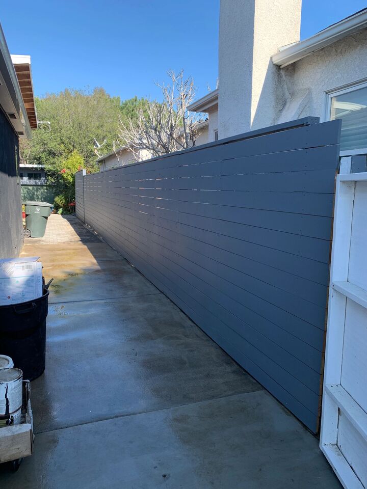 Dark horizontal slat fence with steel posts running the length of a narrow side passage