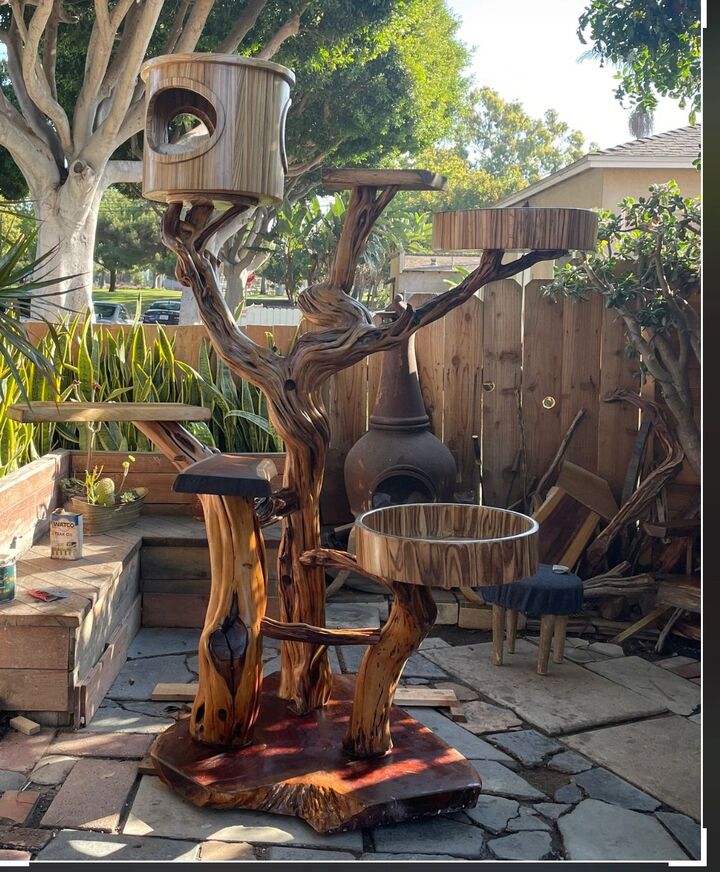 Tall cat tree built from a branching trunk with platforms and an enclosed den box in a garden