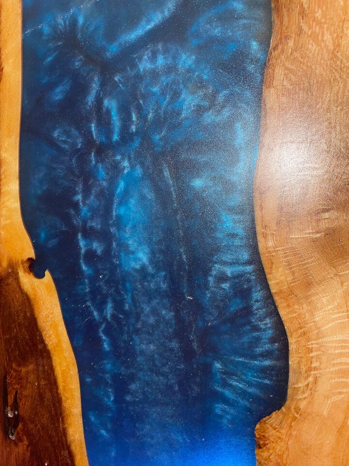 Close detail of deep blue resin meeting the natural live edge of the walnut slab