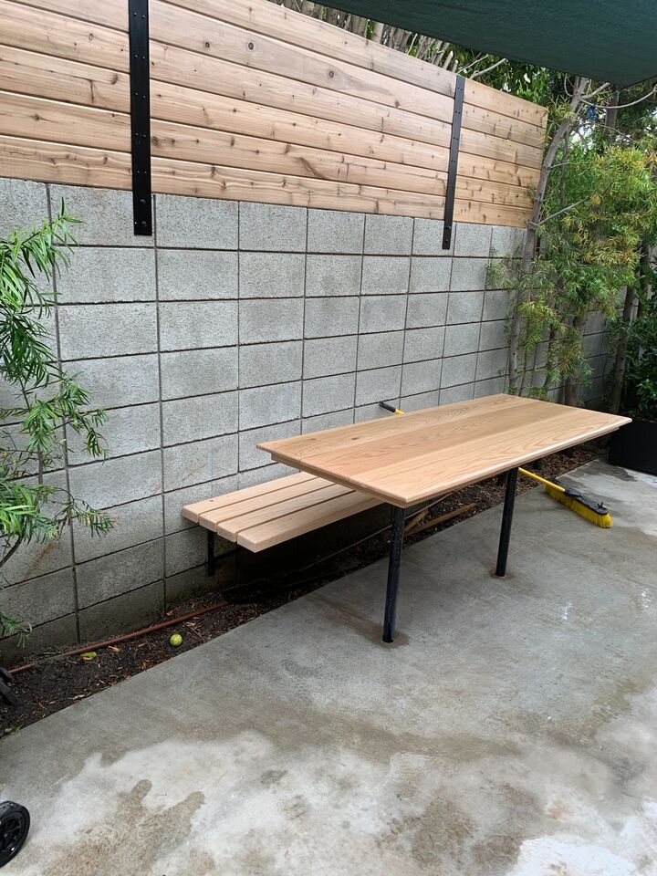 Long hardwood bench on a steel frame set against a fence and block wall