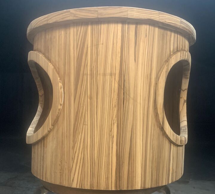 Turned hardwood stool with curved cut-out handles, photographed against a dark background