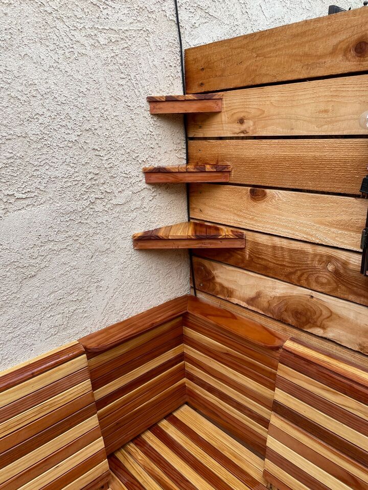 Corner detail of a redwood clad wall with floating shelves and a herringbone bench base