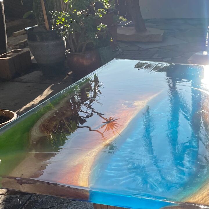 Resin table top poured to resemble turquoise ocean water washing over pale sand
