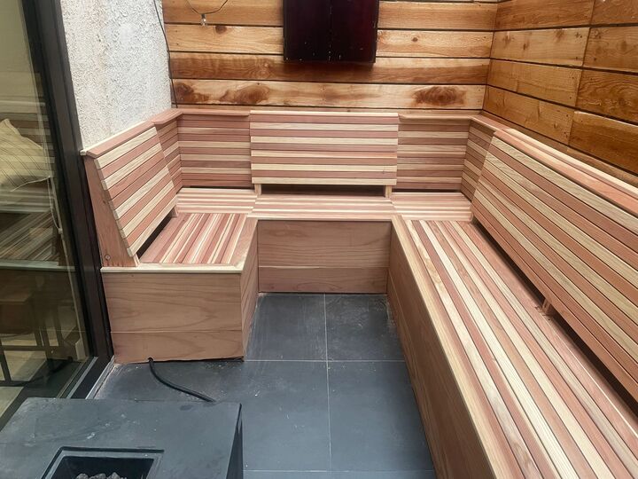 Redwood built-in bench wrapping two walls of a patio corner, with matching horizontal redwood cladding on the wall behind