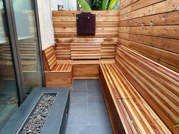 Corner view of the finished redwood bench seat and backrest against a horizontal redwood wall, with a mailbox mounted above