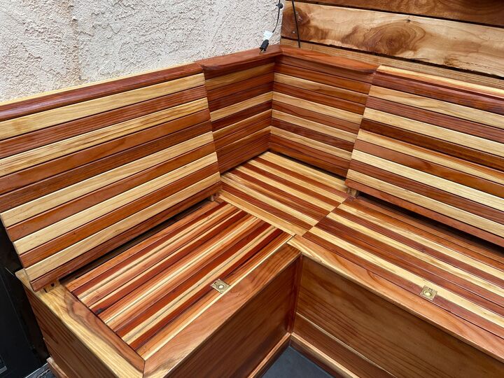 Finished redwood corner bench with storage lids closed, seat boards running the length of both walls