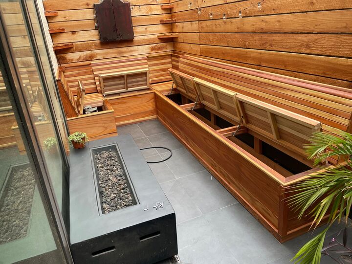 Redwood bench with storage compartments open, showing the framed cavities beneath each hinged seat panel