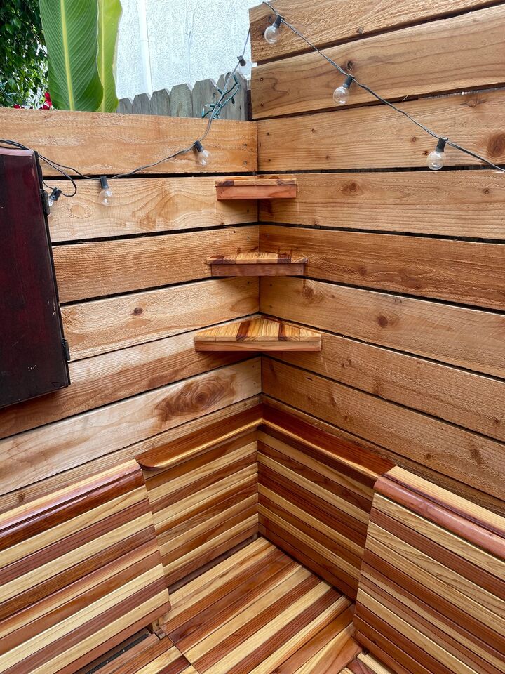 Redwood bench corner with string lights above and shelving built into the clad wall