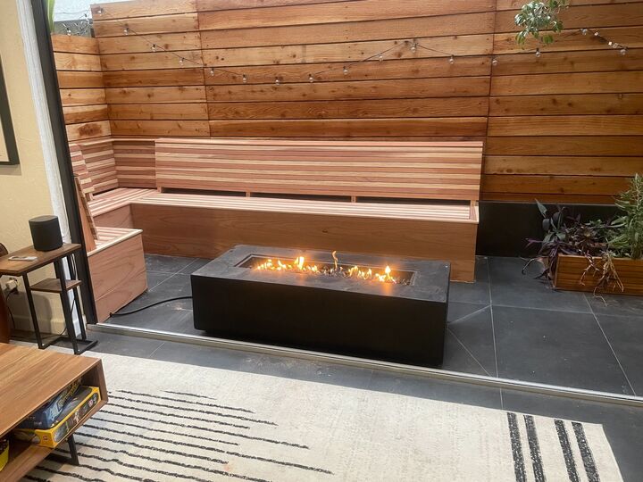 Long redwood bench running along a clad wall beside a modern linear fire table