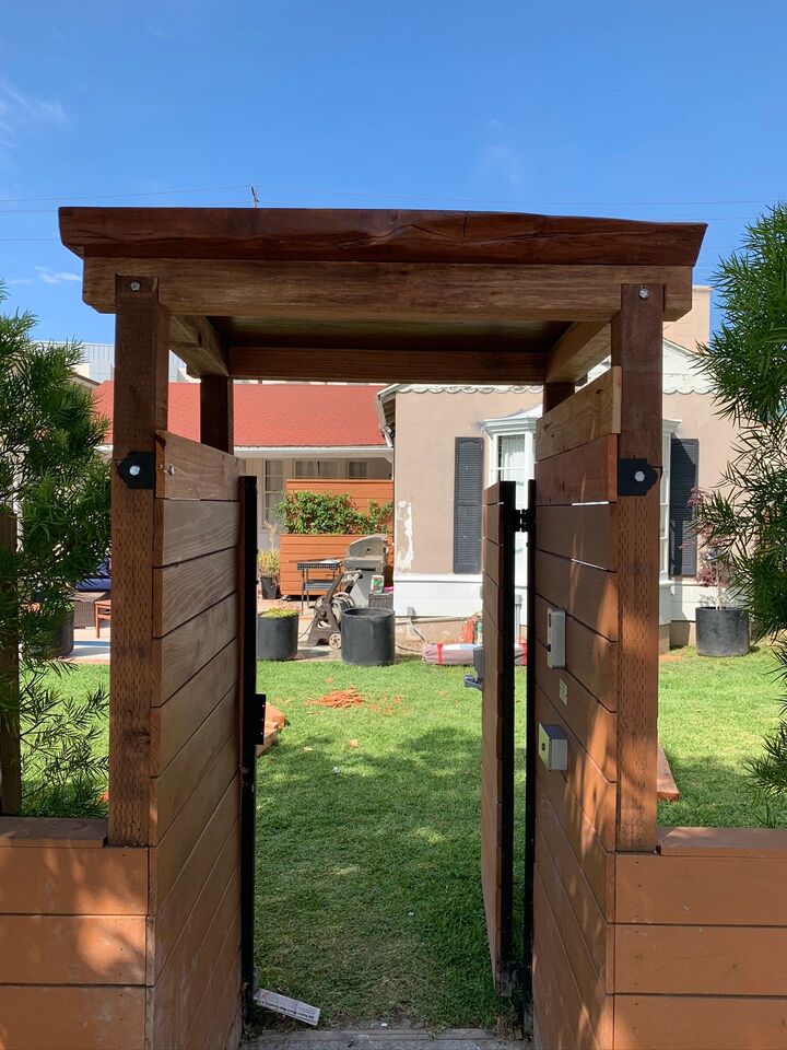 Heavy timber entry arbor over an open redwood gate looking through to a lawn