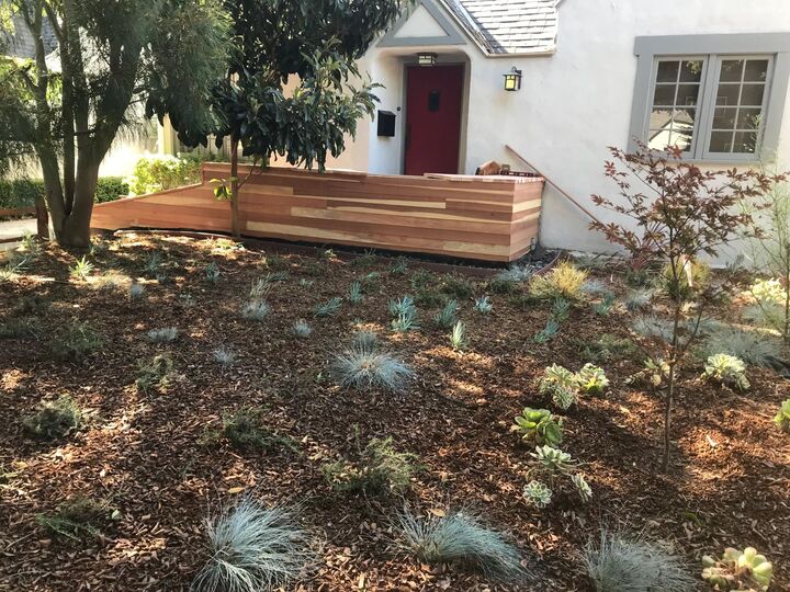Long redwood planter box built along a garden bed with new low planting in front