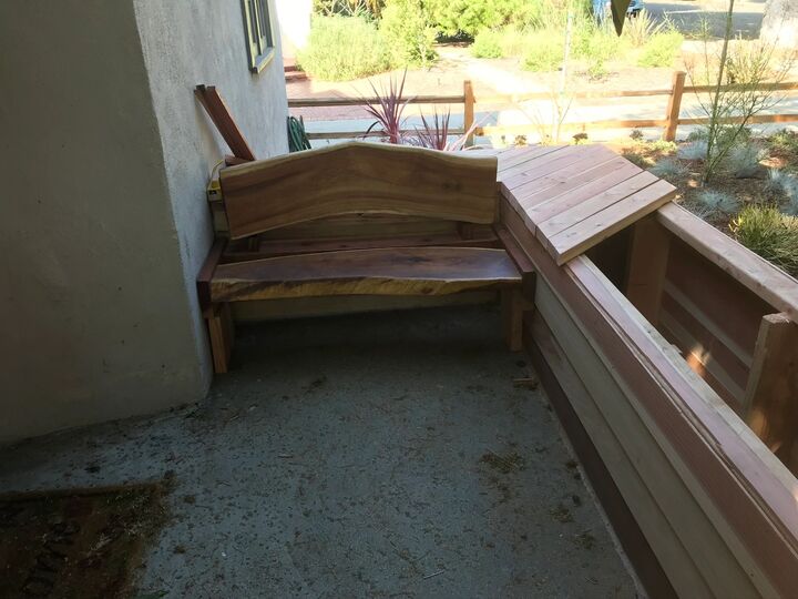Curved redwood bench and planter under construction against a garden wall