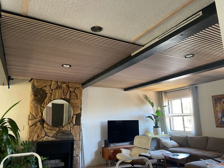 Living room with a full timber slat ceiling, stone fireplace and round mirror