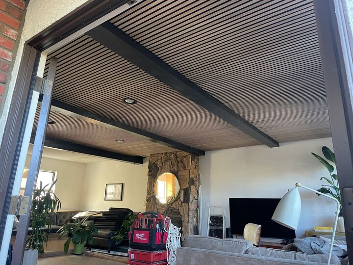 Wide view of the slatted ceiling meeting the black steel beam above an open-plan living space