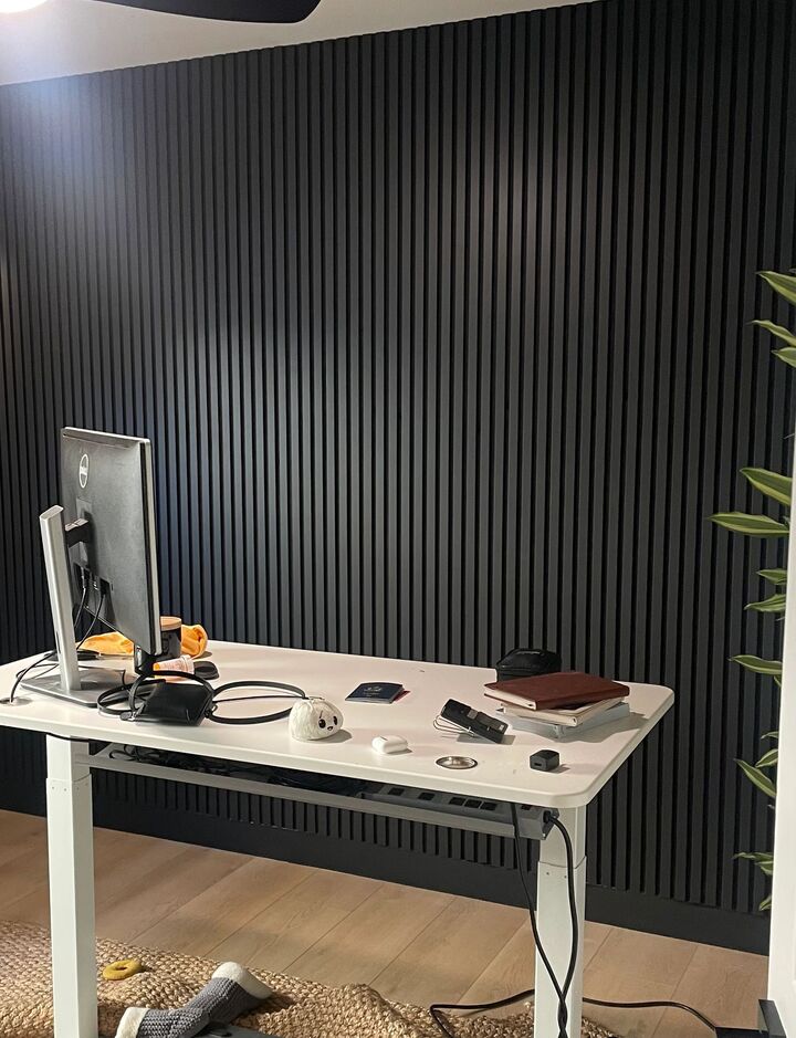 Dark vertical slat feature wall behind a desk in a bedroom