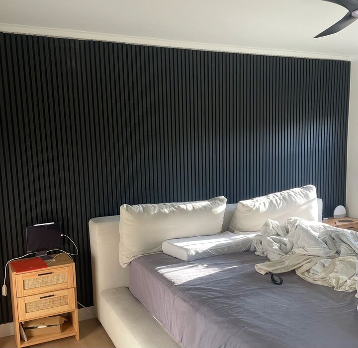 Dark slat feature wall running the full width behind a bed with side tables