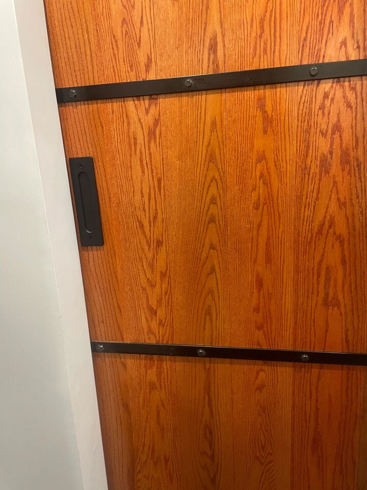 Close detail of the black strap hardware and flush pull on the sliding barn door