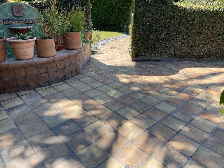 Paved patio area with a curved brick planter wall holding terracotta pots