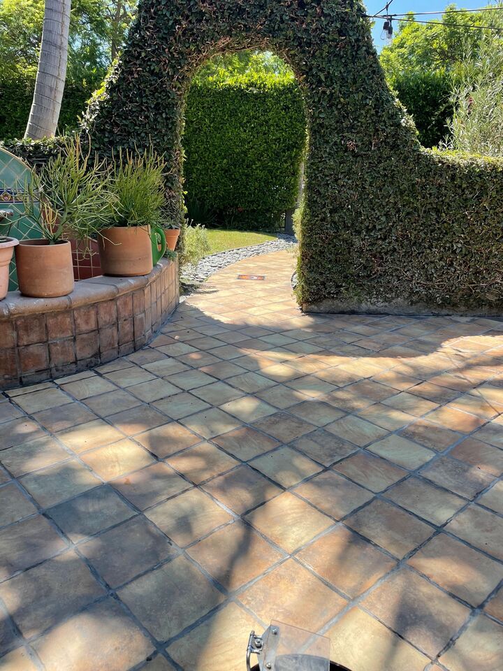 Terracotta tiled patio seen through a clipped hedge archway