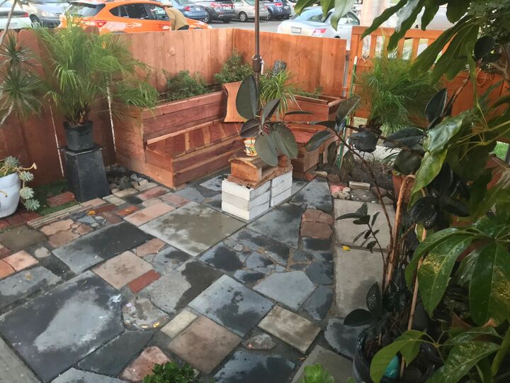 Mixed stone patio with planting and a timber bench against a fence
