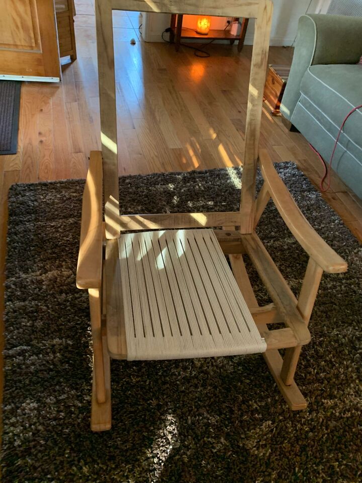 Slatted timber bench chair on a rug beside a fireplace