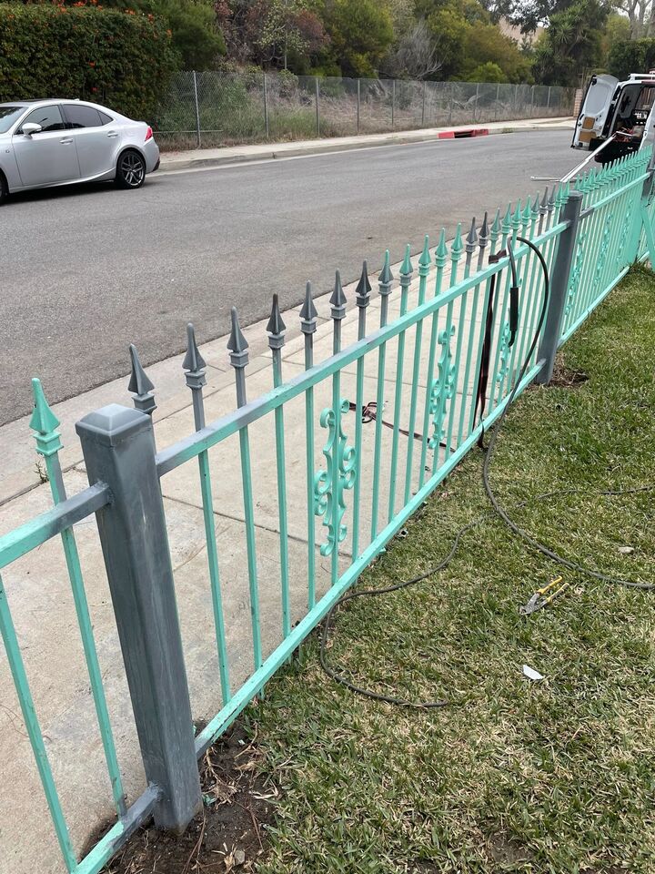 Repaired wrought iron fence reinstalled along a street frontage with the posts back in plumb